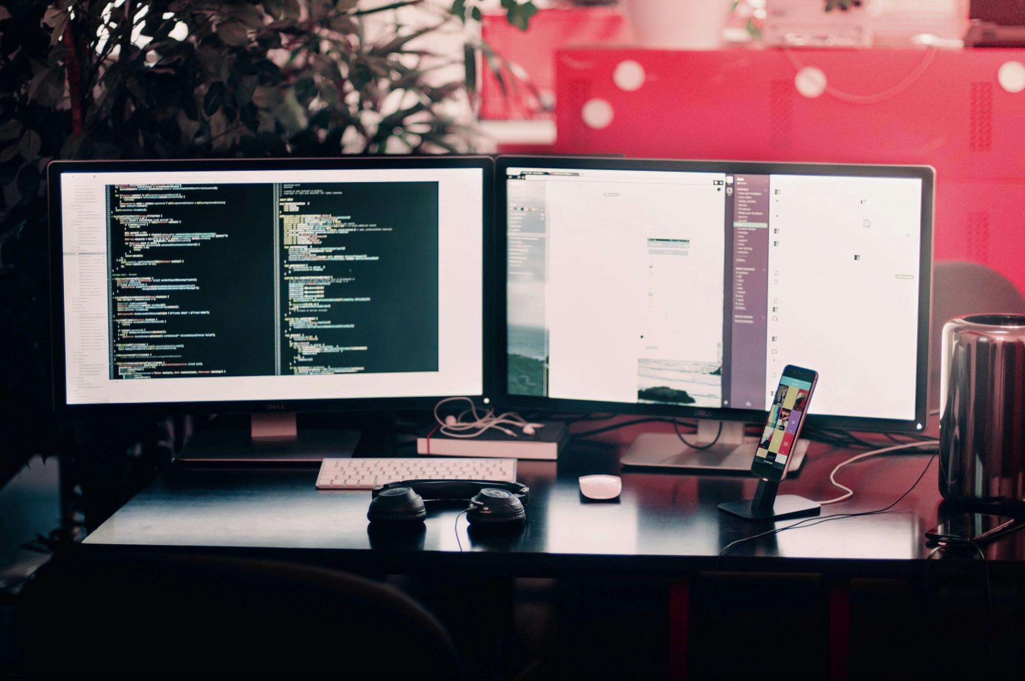 image of two desktop computers and one mobile phone set up on desk for a web developer, code on screen