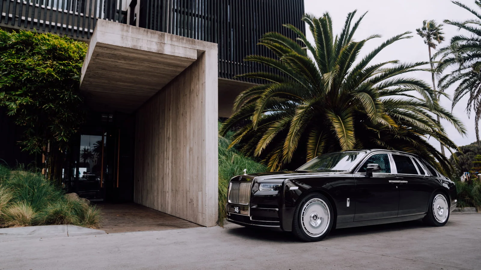 Image of black Rolls Royce in front of tropical building